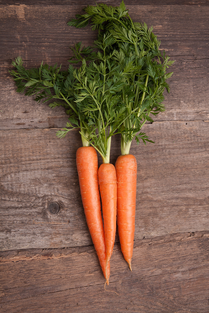 fresh-carrots-with-green-tops-on-wood-table
